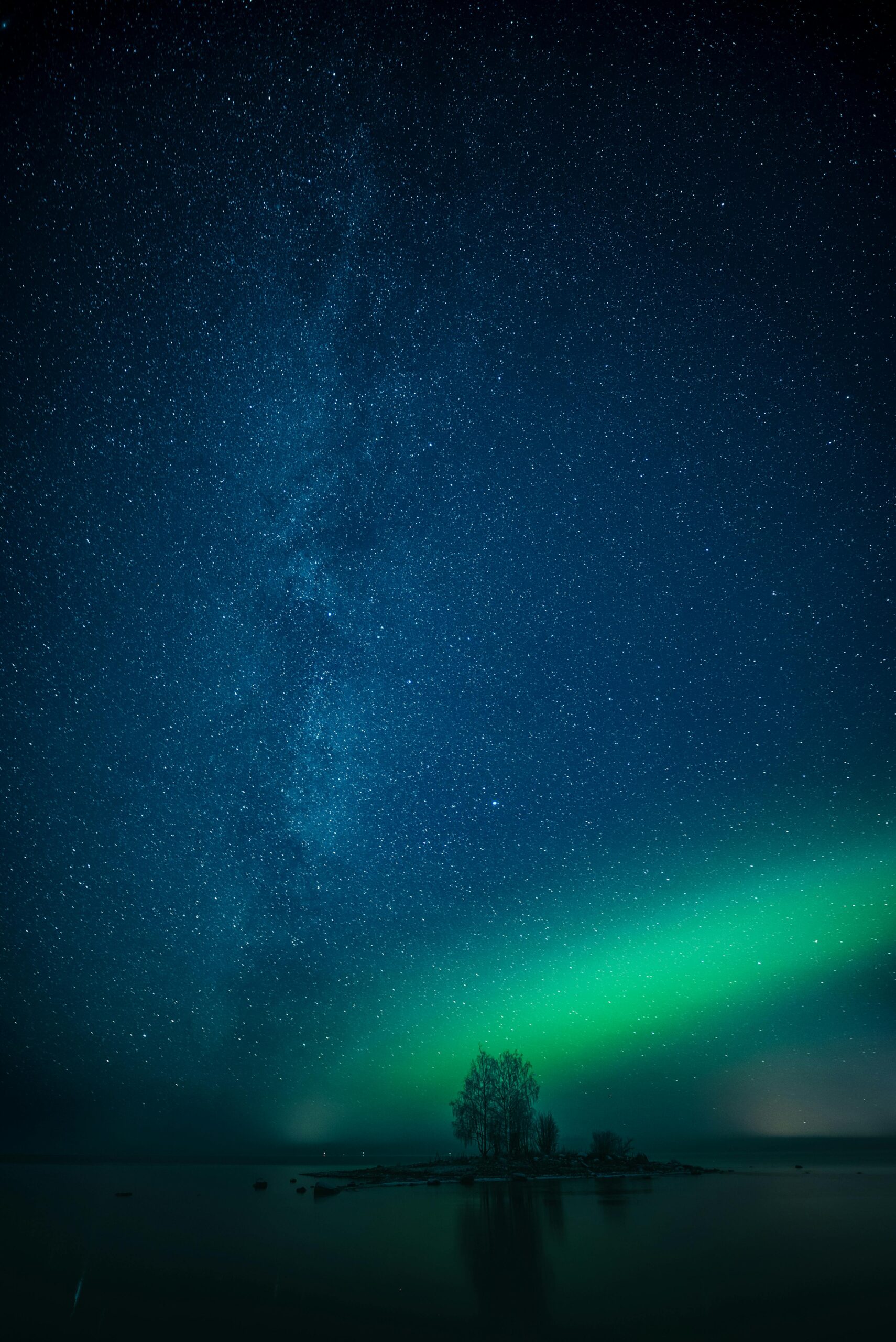 Magnificent view of the Northern Lights and Milky Way over a serene Finnish lake in Oulu.