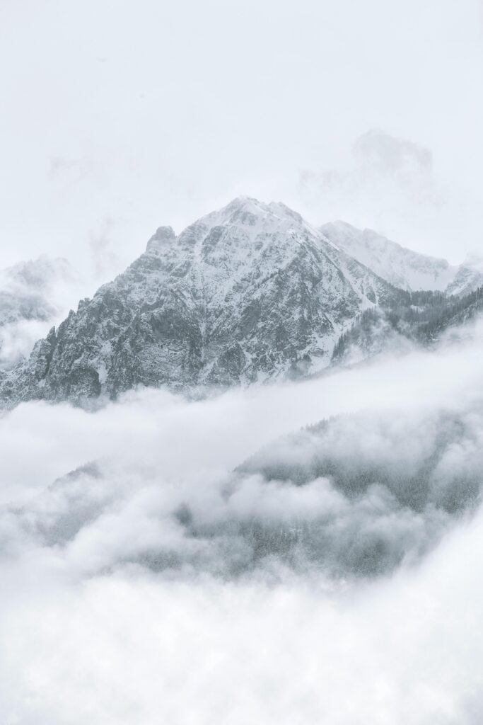 Breathtaking winter scene of a snow-covered mountain peak surrounded by misty clouds.